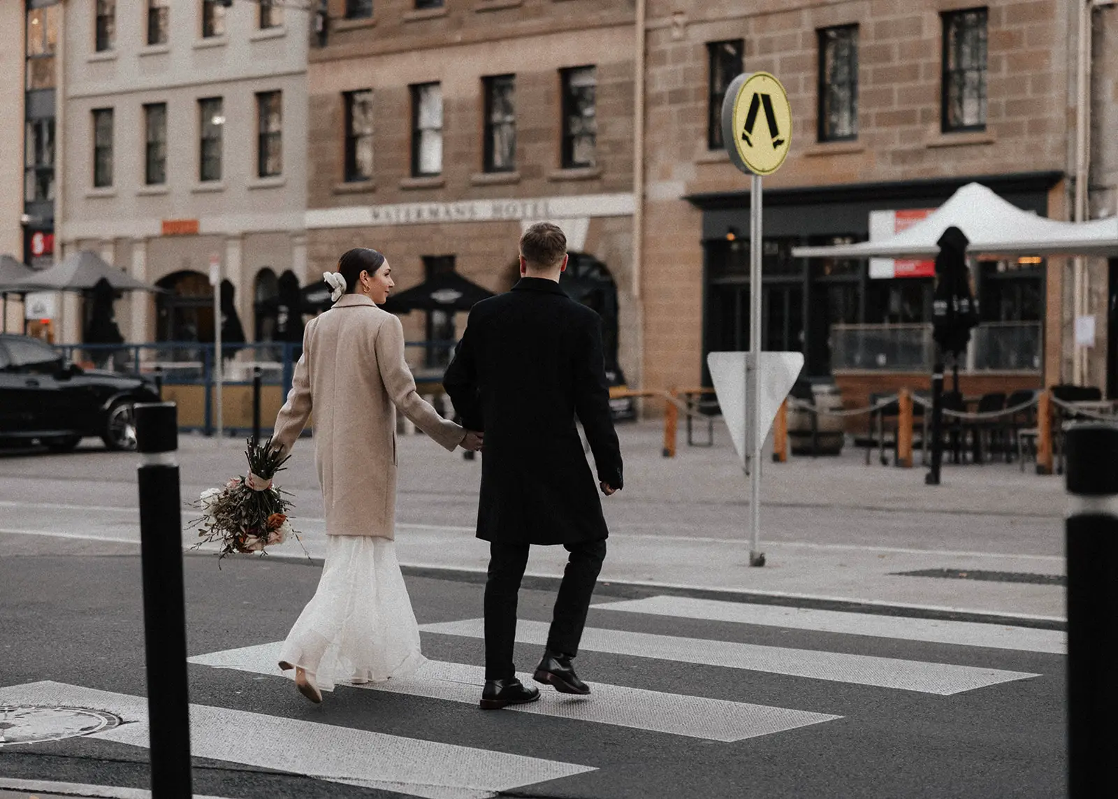 A bride and groom stand together in the heart of Hobart, Tasmania, sharing vows with their wedding celebrant, Josh Withers. The scene is set against the historic city’s greenery and timeless beauty.